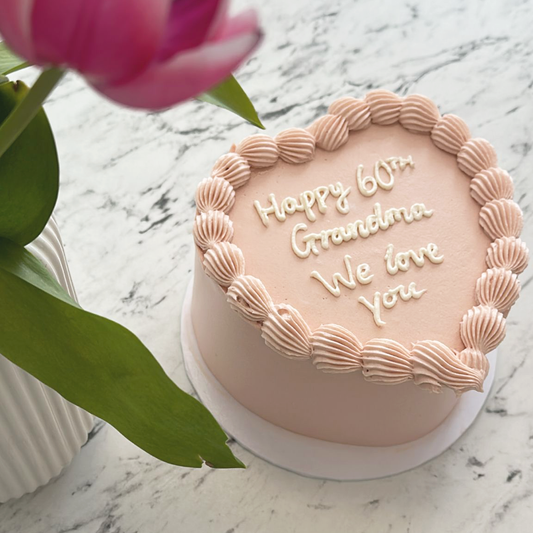 Rose pink heart vintage cake, with 'happy 60th birthday grandma' message piped in white icing. 